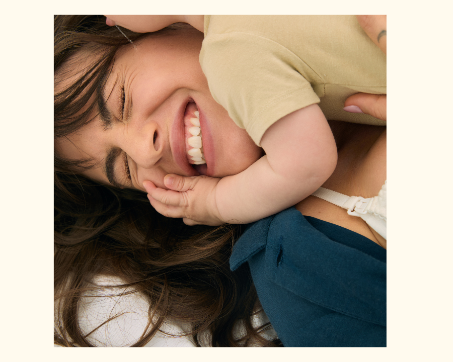 A mom smiling while receiving cuddles from her toddler