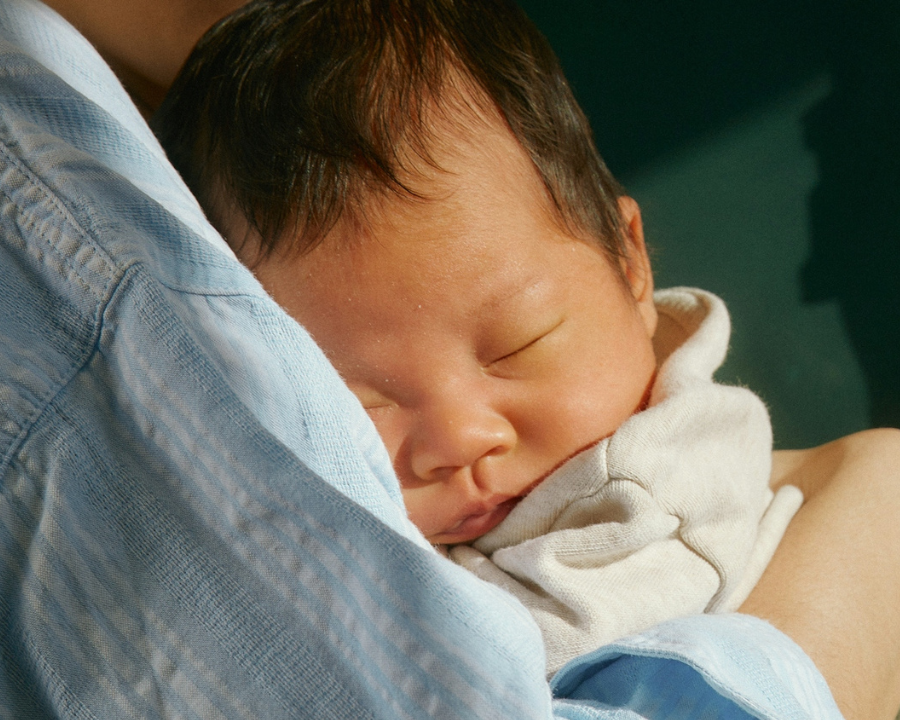 A very young baby sleeping while being held A very young baby sleeping while being held