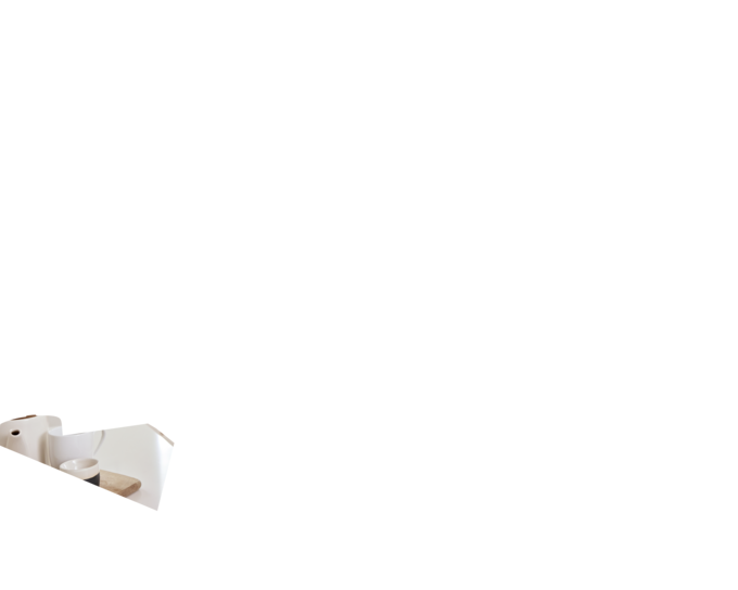 Eine kaffeetrinkende Mutter steht in der Küche und trägt die Medela Freestyle™ Hands-free double electric wearable breast pump