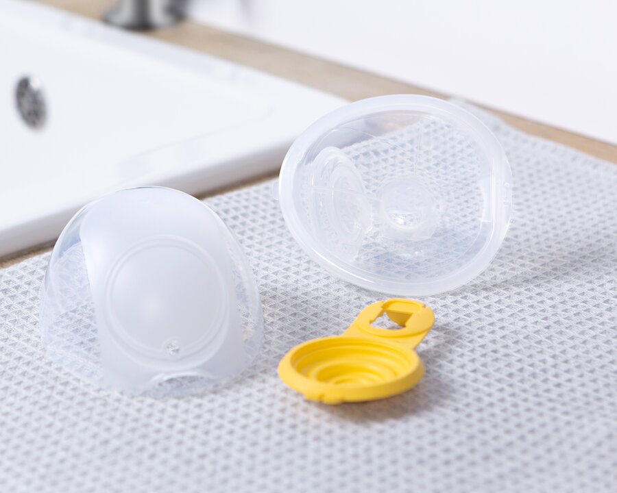 3 easy to assemble pieces of Medela Freestyle™ Hands-free double electric wearable breast pump's collection cups on drying mat on counter