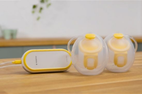 Medela Freestyle™ Hands-free double electric wearable breast pump and collection cups sitting on counter
