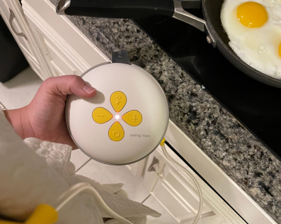 Woman wearing Swing Maxi Hands-free breast pump and cooking eggs.