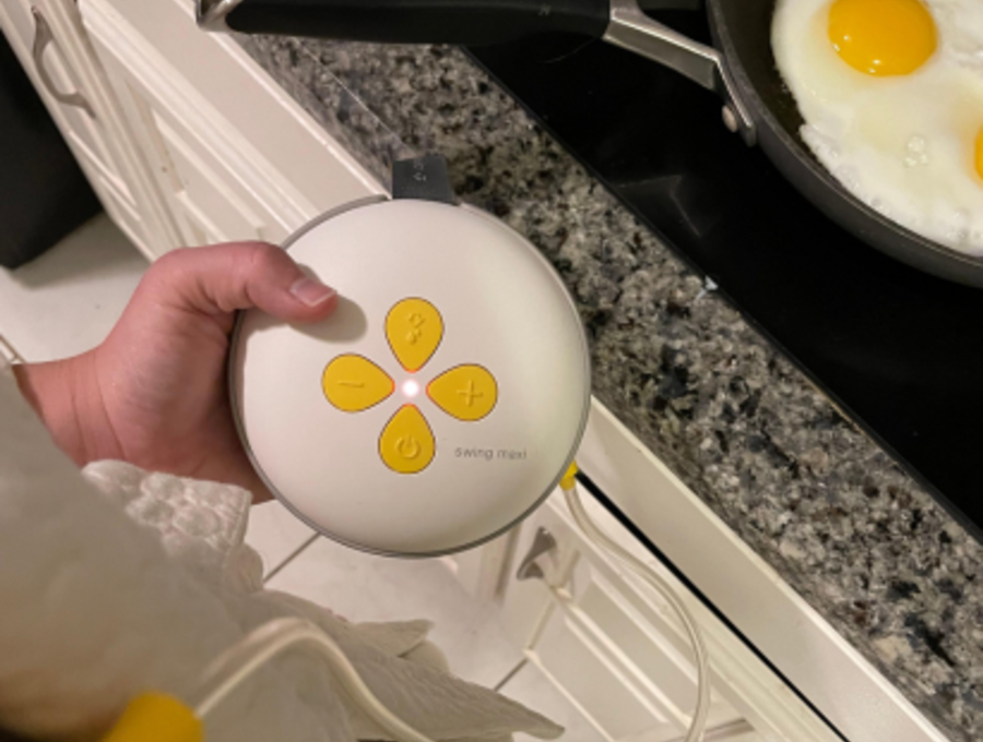 Woman wearing Swing Maxi Hands-free breast pump and cooking eggs.