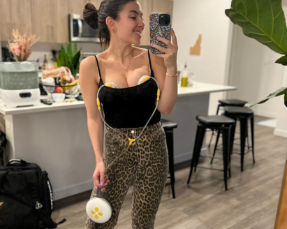 Woman standing in kitchen taking a selfie while pumping with Swing Maxi hands-free breast pump.