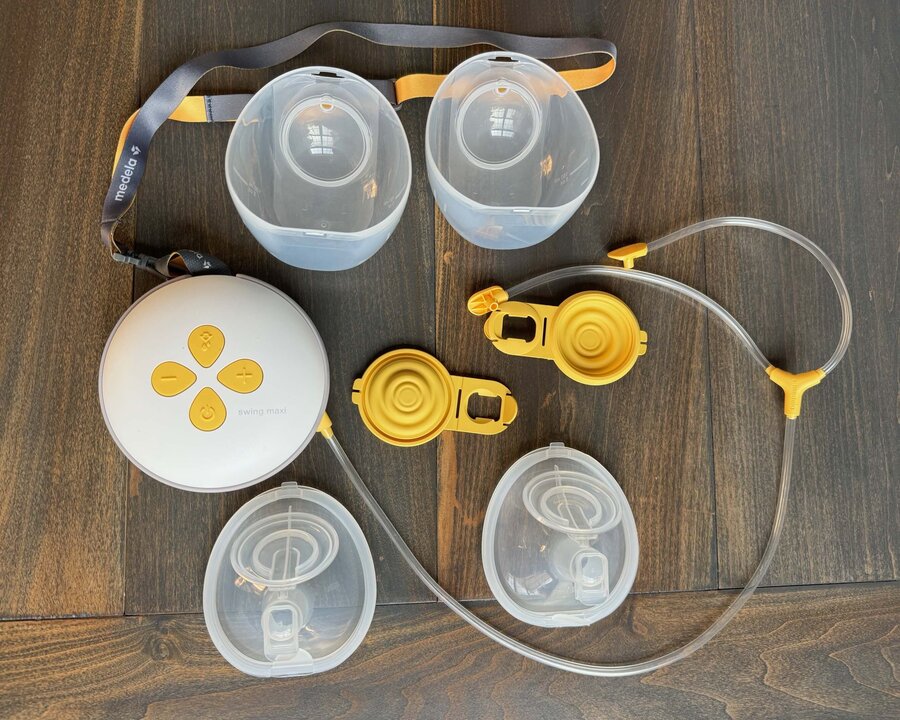 Medela Swing Maxi Hands-free breast pump with its parts laying on a table.