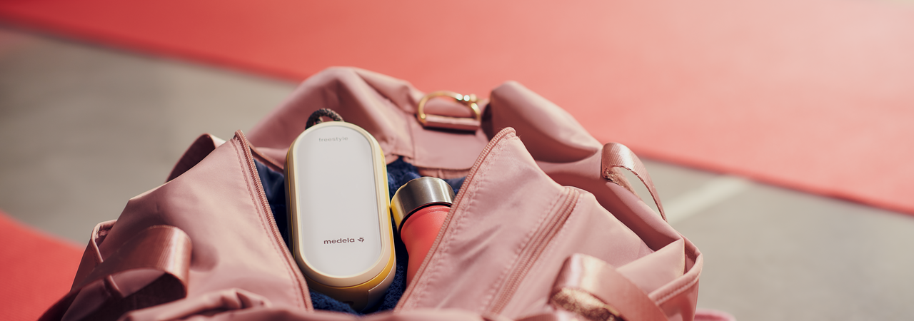 Medela Freestyle Flex™ Two-phase double electric breast pump sitting in the top of a mom's purse