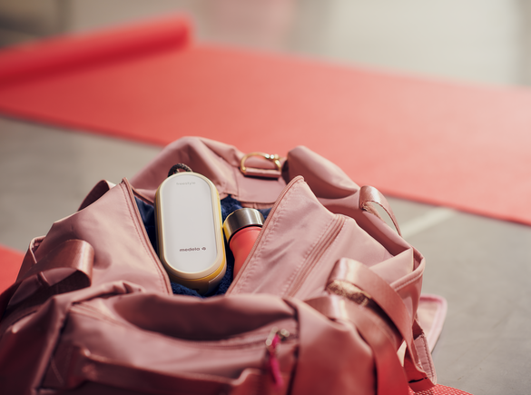 Medela Freestyle Flex™ Two-phase double electric breast pump sitting in the top of a mom's purse