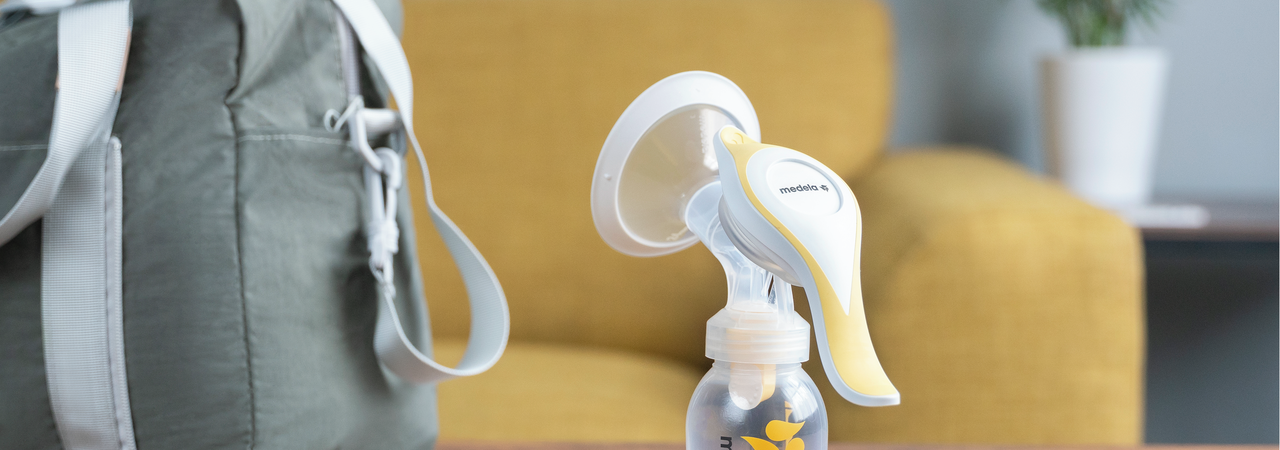 The Medela Harmony™ manual breast pump on a table at home ready to go with keys, glasses and diaper bag.