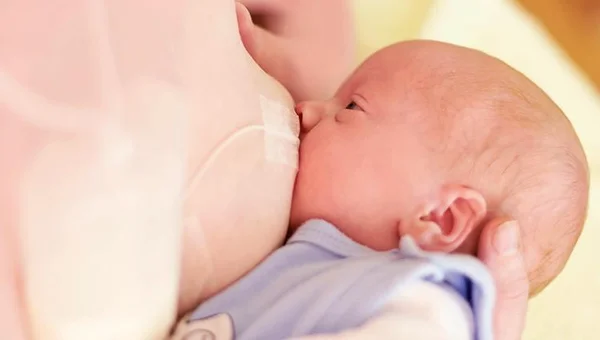 Una mamma che allatta al seno il suo bambino e integra la dieta con il Sistema di allattamento supplementare™ (SNS) di Medela.
