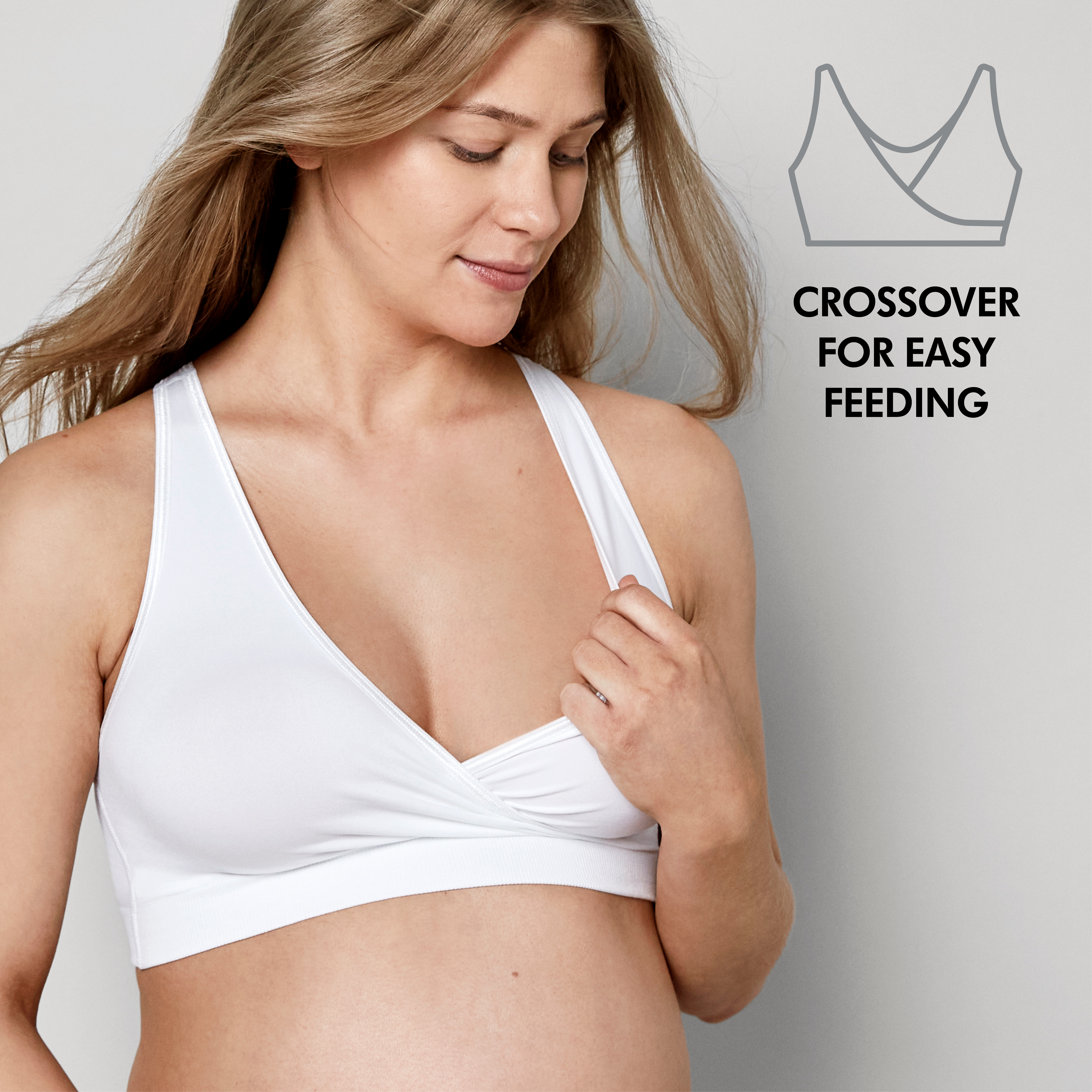 A woman wears a Medela Keep Cool™ Sleep Bra White, front view with the text “Crossover for easy feeding”.