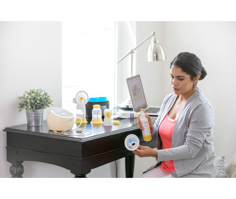 A Mom disinfects her breast pump and accessories with the Medela Quick Clean™ Breast Pump & Accessory Sanitizer Spray after pumping at work 