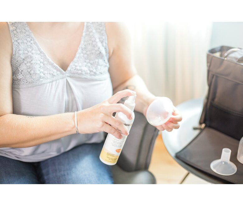 Close-up of a Mom disinfecting her accessories after pumping at home with the Medela Quick Clean™ Breast Pump & Accessory Sanitizer Spray