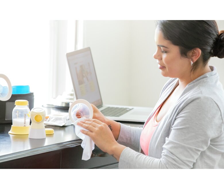 A Mom disinfects her breast shield and pump parts after pumping at work with the Quick Clean™ breast pump and accessory wipes.