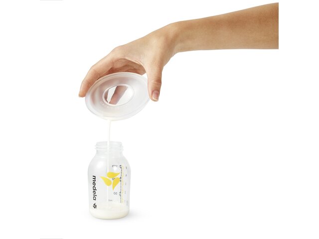 Pouring breast milk from the Medela Milk Collection Shells into a breast milk storage bottletle