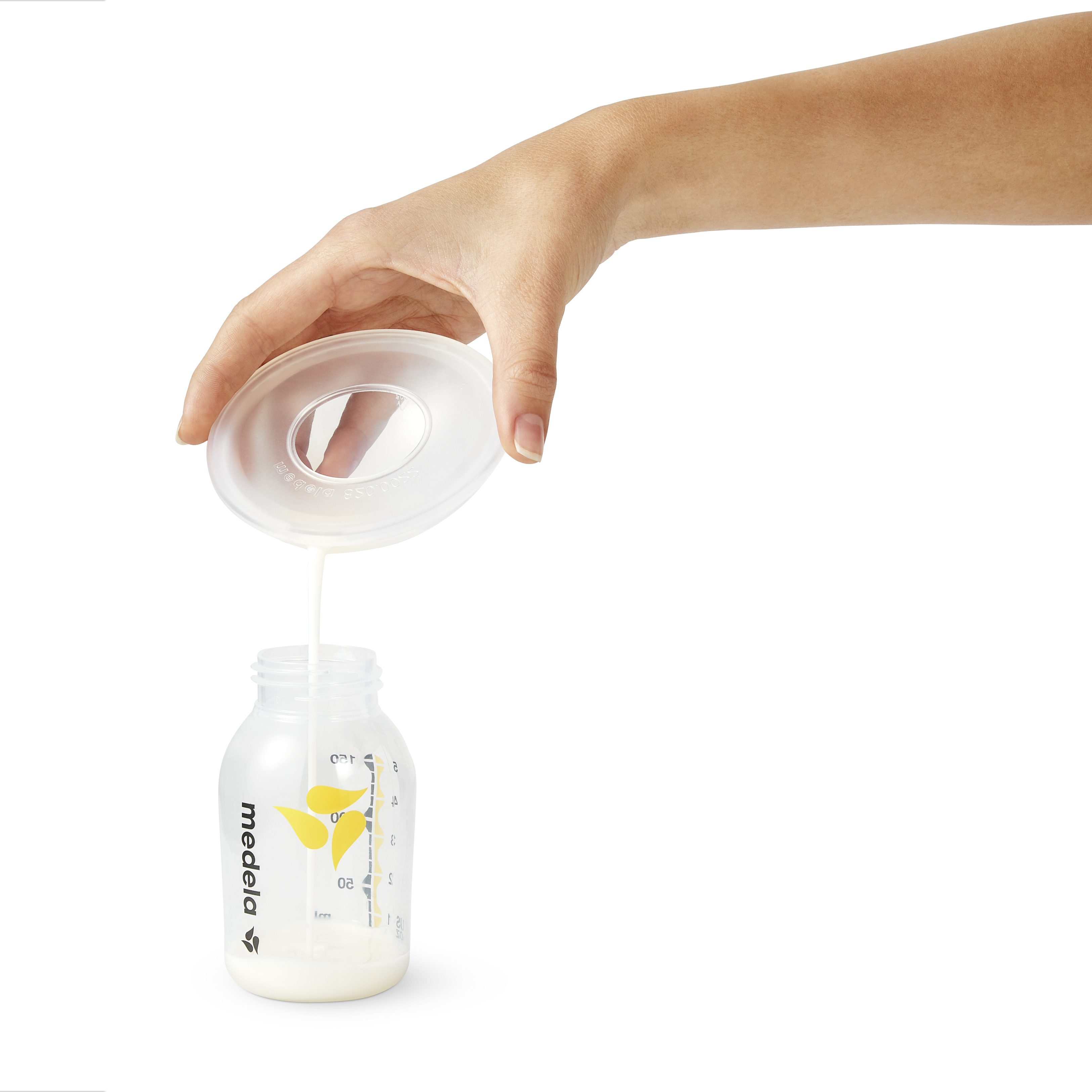 Pouring breast milk from the Medela Milk Collection Shells into a breast milk storage bottletle