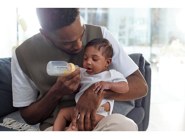 Een baby wordt gevoed door zijn vader met een Medela Softcup™.