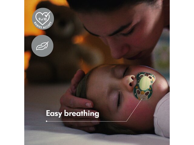 A sick child uses a Medela NIGHT dummy while lying in bed with his mom. Text: 'Easy breathing'. Symbols: “9 out of 10 Babies Accept”, 'Lightweight'.