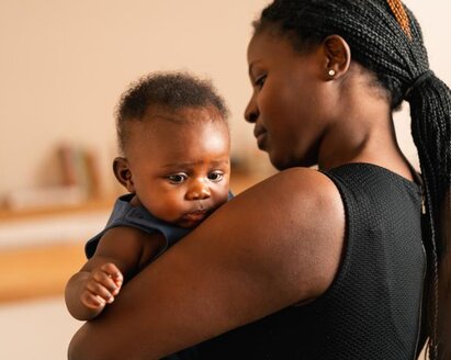 Eine Mutter hält ihr Baby zu Hause im Arm.