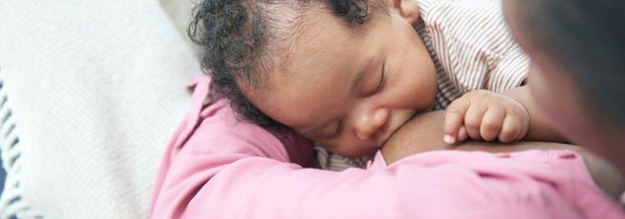 Ein Baby, das zu Hause auf dem Schoß seiner Mutter gestillt wird.