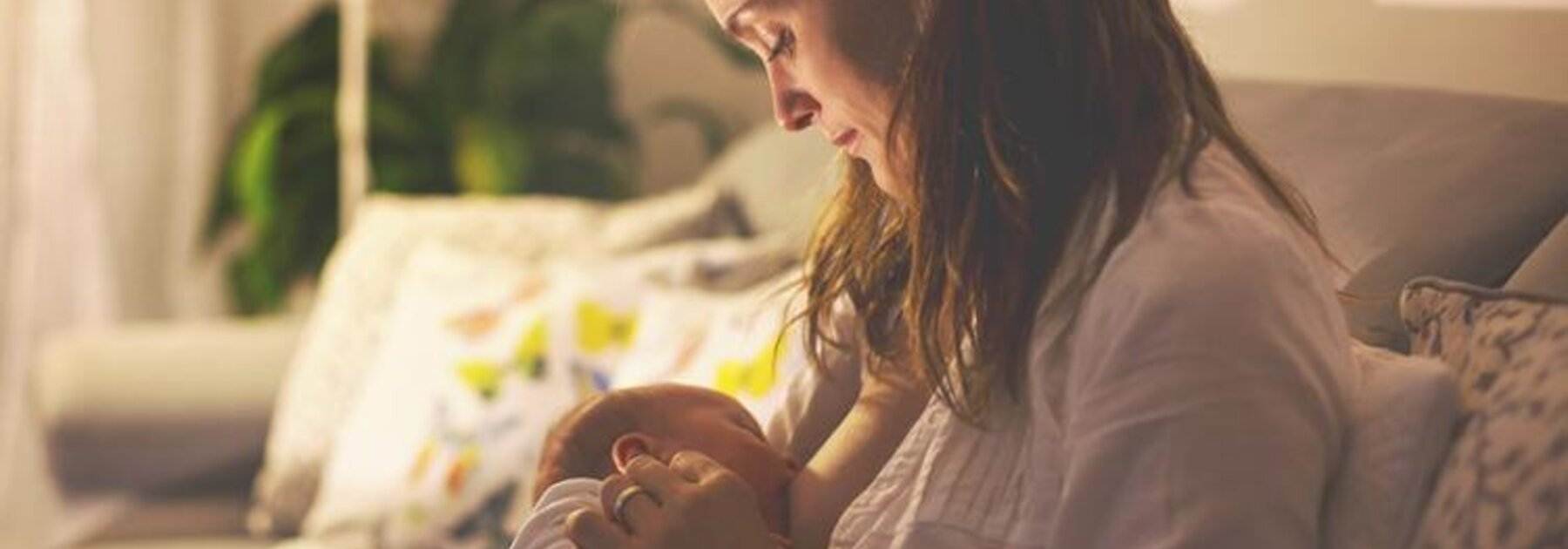 Breastfeeding Lifestyle A mom breastfeeding her baby at night in her living room with the lights dimmed.