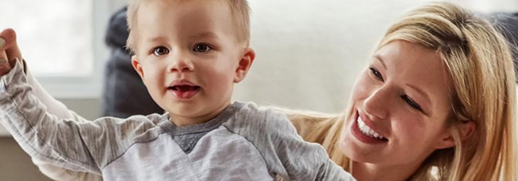 A smiling mom helps a boy learn to stand, then walk.