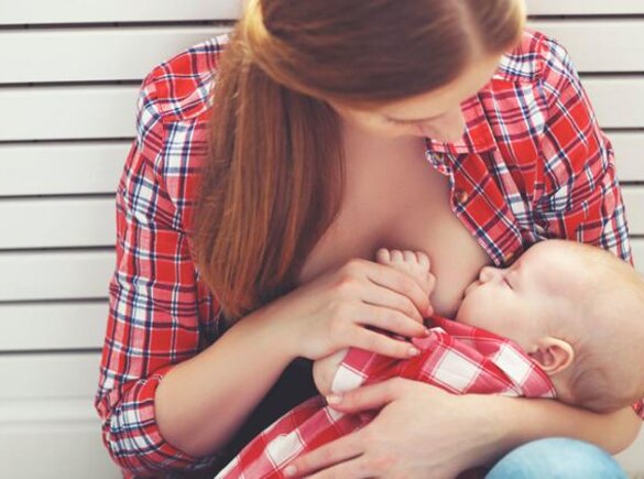 A young mother nurses her baby while looking down.