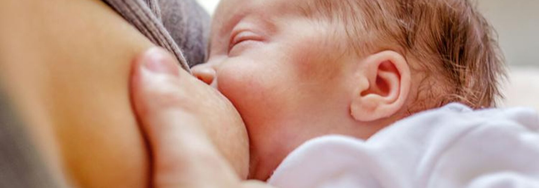 Nahaufnahme einer Mutter, die ihr neugeborenes Kind stillt.