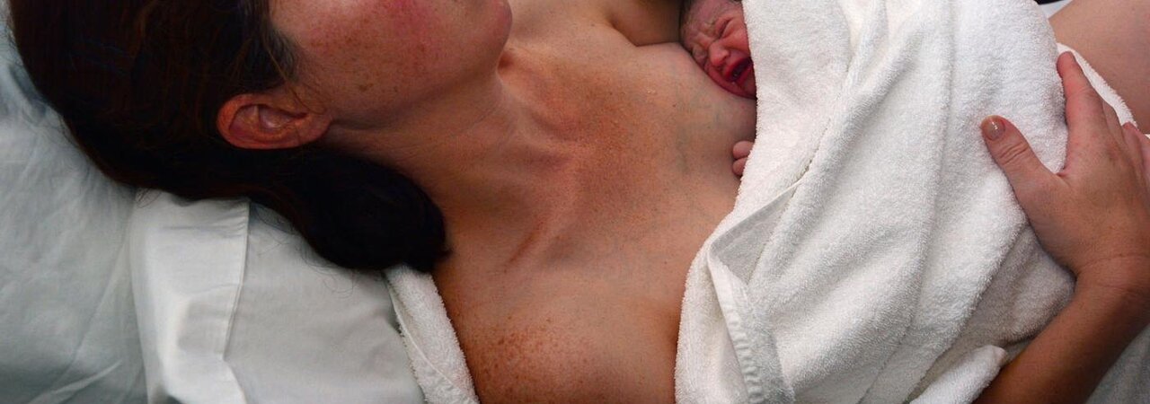Eine Mutter hält ihr in ein Handtuch gewickeltes Baby unmittelbar nach der Geburt.
