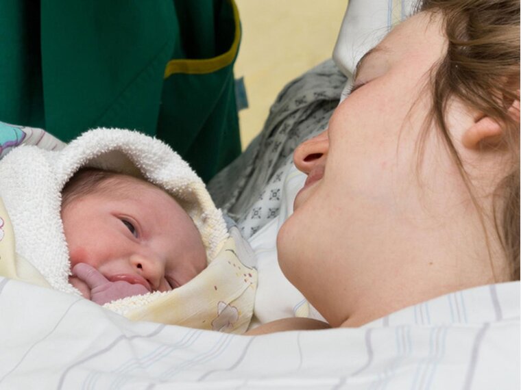 Eine Mutter und ihr Baby liegen nach der Entbindung in einem Krankenhausbett.