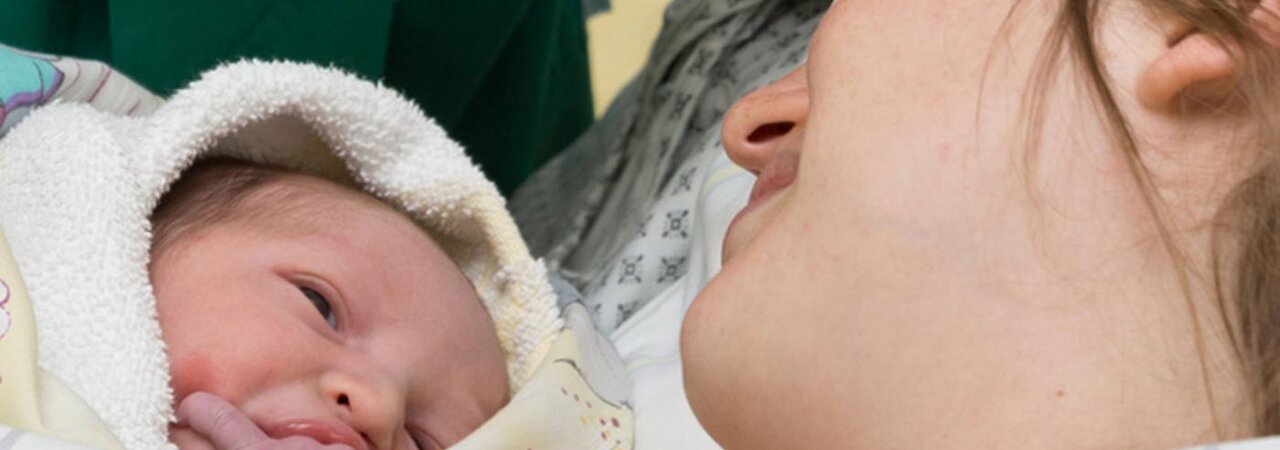 Eine Mutter und ihr Baby liegen nach der Entbindung in einem Krankenhausbett.