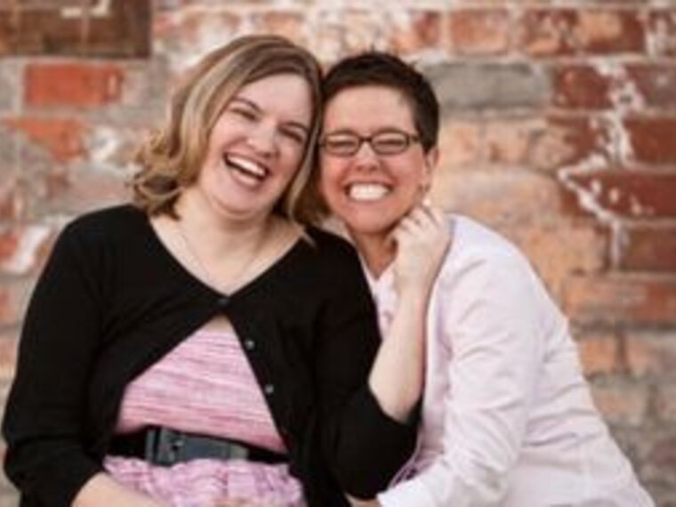 A smiling couple sitting outside.