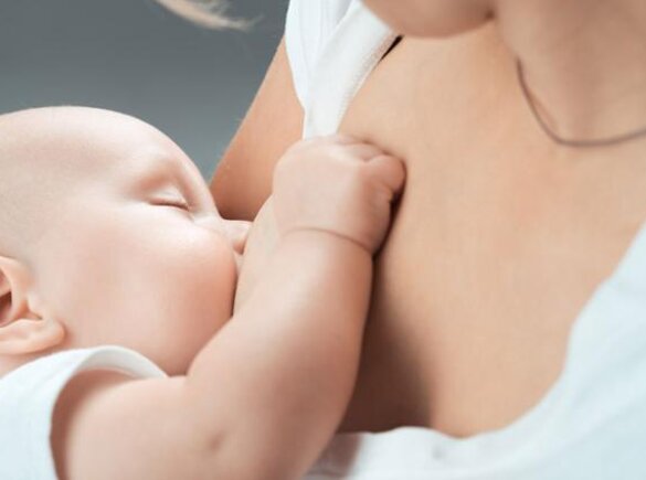 Close-up of a sleeping baby being breastfed.