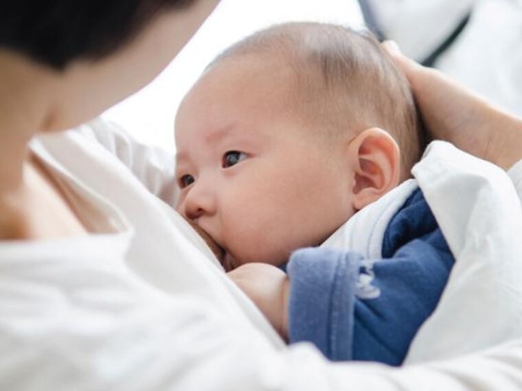 A mother cradles her baby while breastfeeding.