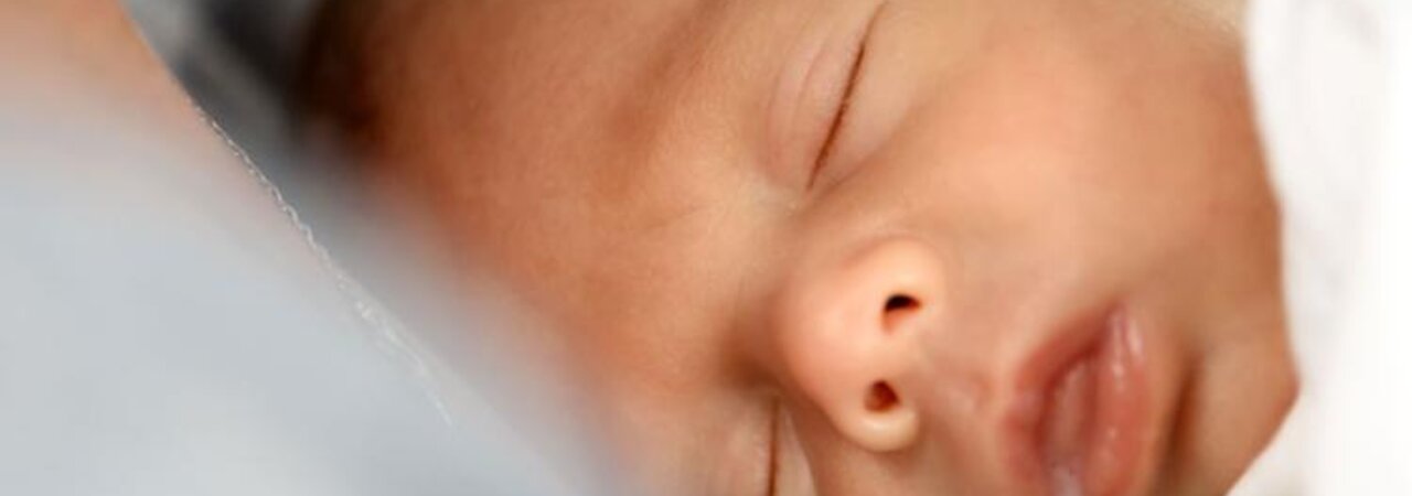 Nahaufnahme des Babys nach dem Stillen, mit Muttermilch an der Seite des Mundes.
