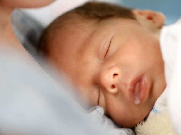 Nahaufnahme des Babys nach dem Stillen, mit Muttermilch an der Seite des Mundes.