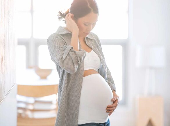 Eine schwangere Frau trägt ein Bauchband.