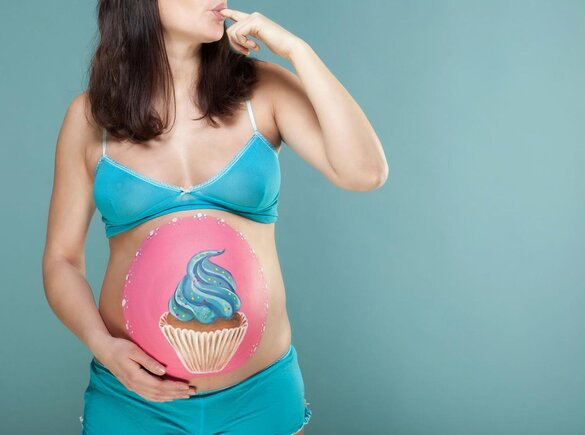 Schwangere Frau mit einem Cupcake auf dem Bauch.