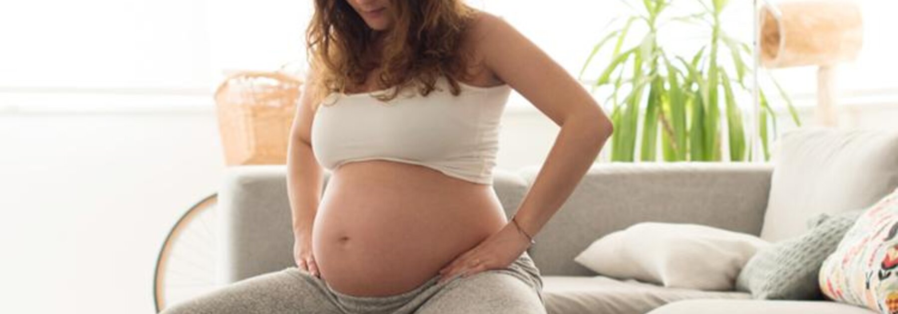 Schwangere Frau, die mit einem Gymnastikball ihren Beckenboden trainiert.