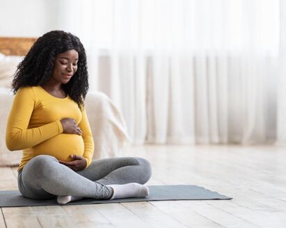 Mamá embarazada sentada en una esterilla de yoga.