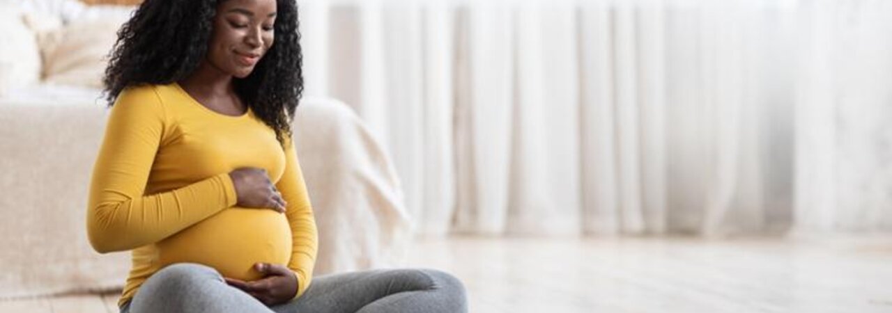 Mamá embarazada sentada en una esterilla de yoga.