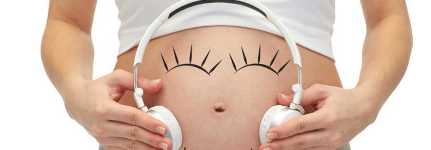Eine Frau hält sich Kopfhörer an den schwangeren Bauch, um Musik zu hören.