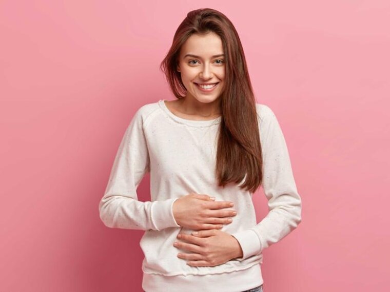 Eine junge Frau hält sich den Bauch.