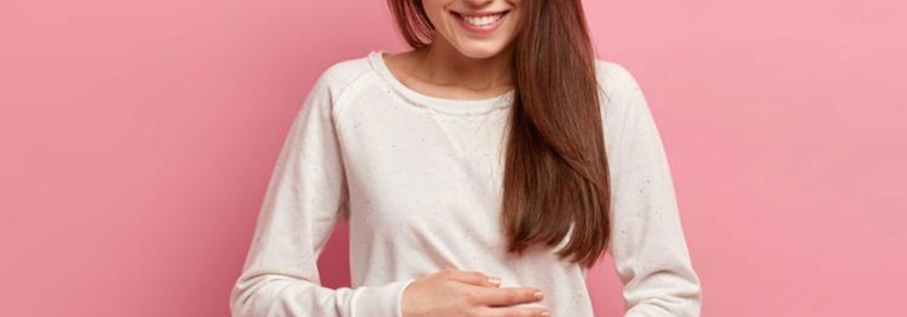 Eine junge Frau hält sich den Bauch.