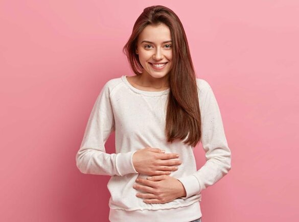 Eine junge Frau hält sich den Bauch.