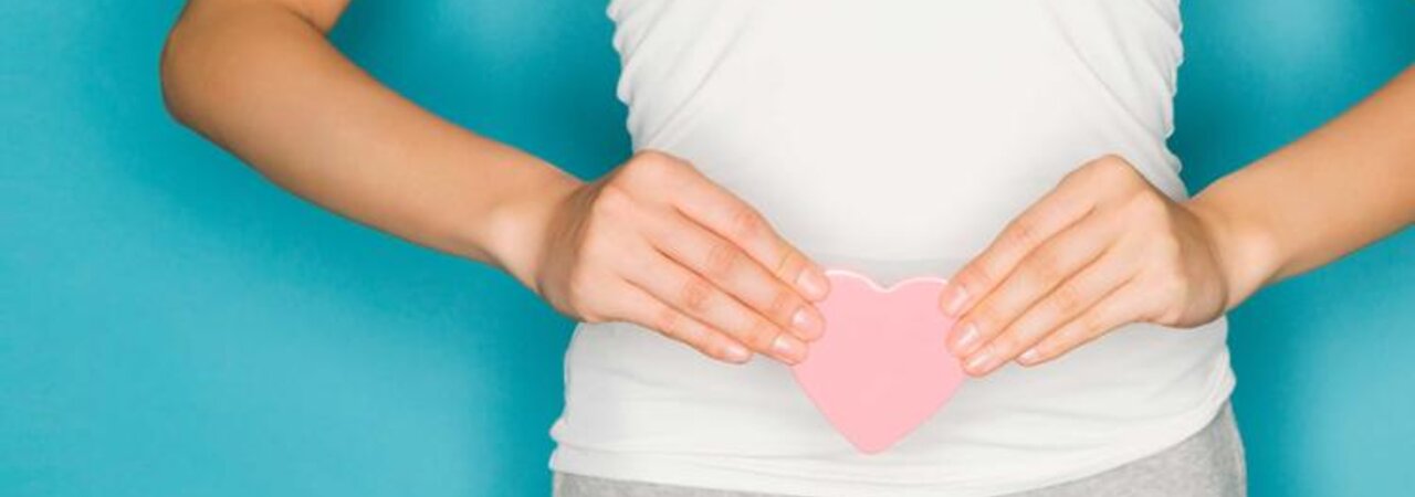 Eine stehende Frau hält sich ein Herz vor den Bauch.