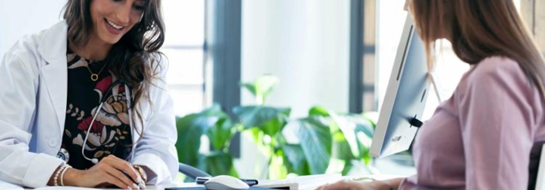 Pregnant woman sitting across the desk from her doctor.