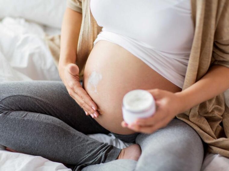 Eine schwangere Frau reibt sich den Bauch ein.