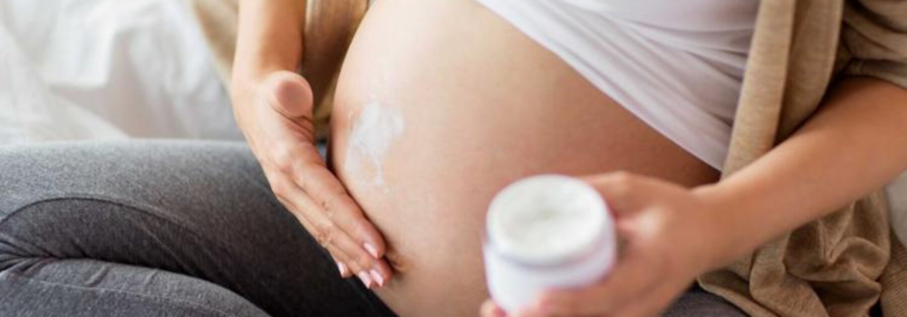 Eine schwangere Frau reibt sich den Bauch ein.