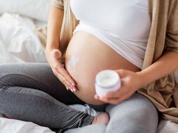 Eine schwangere Frau reibt sich den Bauch ein.