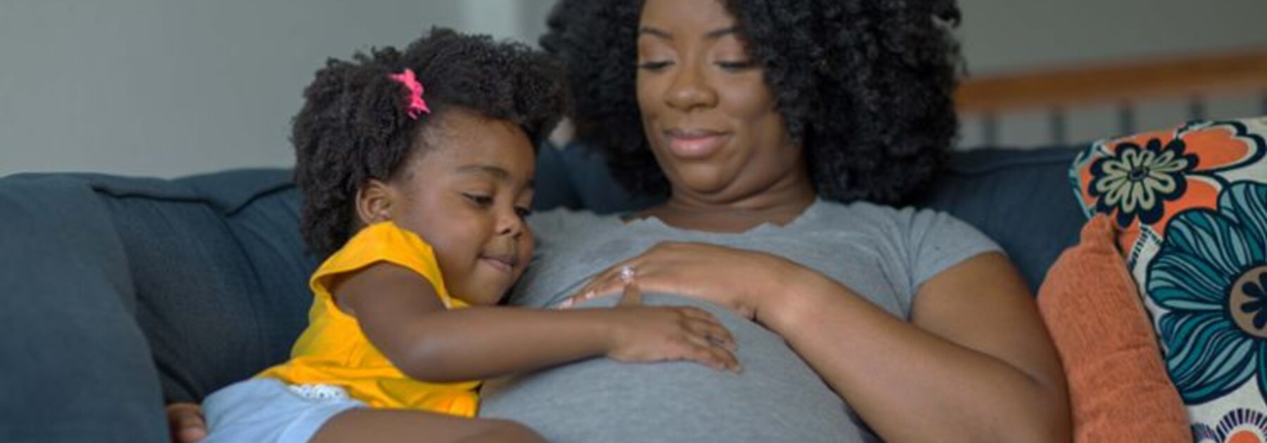 Een zwangere moeder die haar buik streelt met haar dochter.